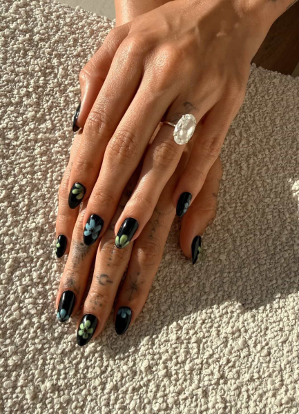 Hailey Bieber shows off a black manicure with blue and green floral design.